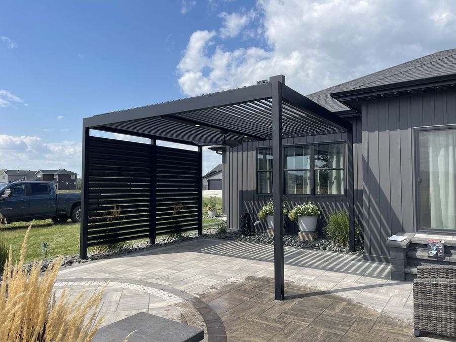 Black pergola with louvered privacy walls beside a dark-sided home
